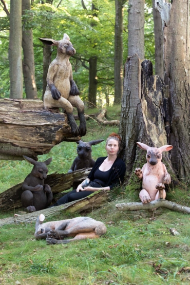 margit Brundin sitter lutad mot ett träd omgiven av sina harar.