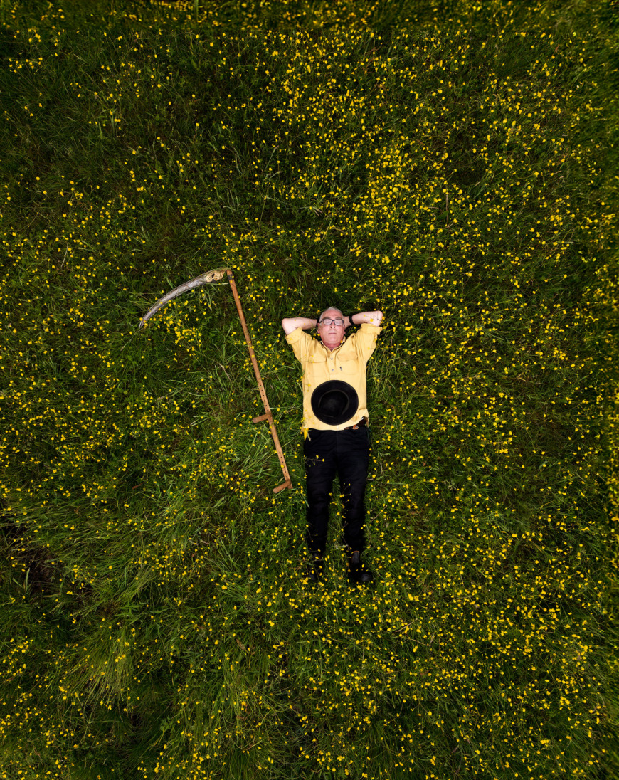 Michael Ritter ligger på en äng med sin lie.