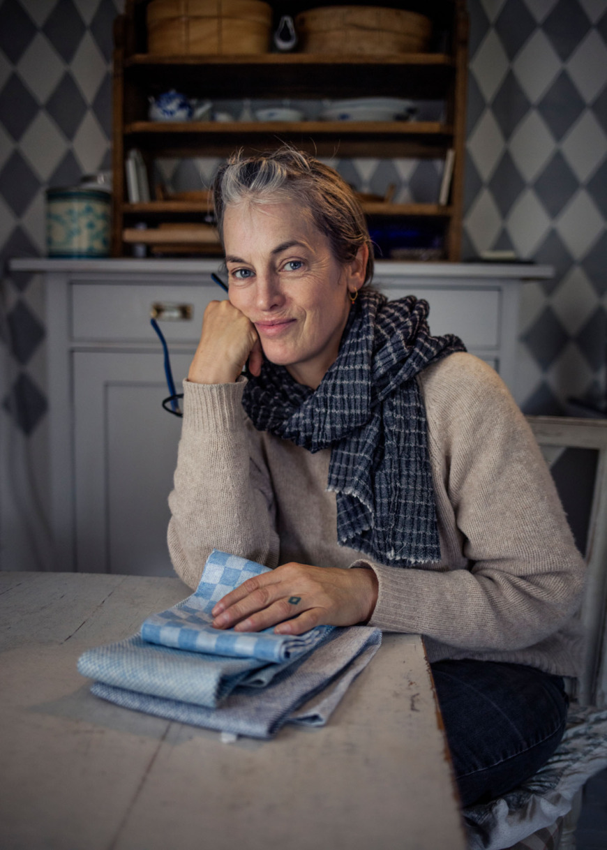 Åsa Pärson sitter vid ett bord med några vävda handdukar.
