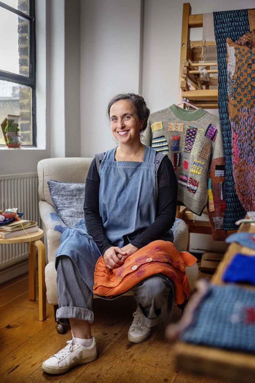 Celia Pym sittandes i en fåtölj med lagningar på armstöden.