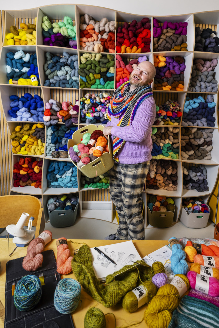 Stephen West framför en hylla full med garn.